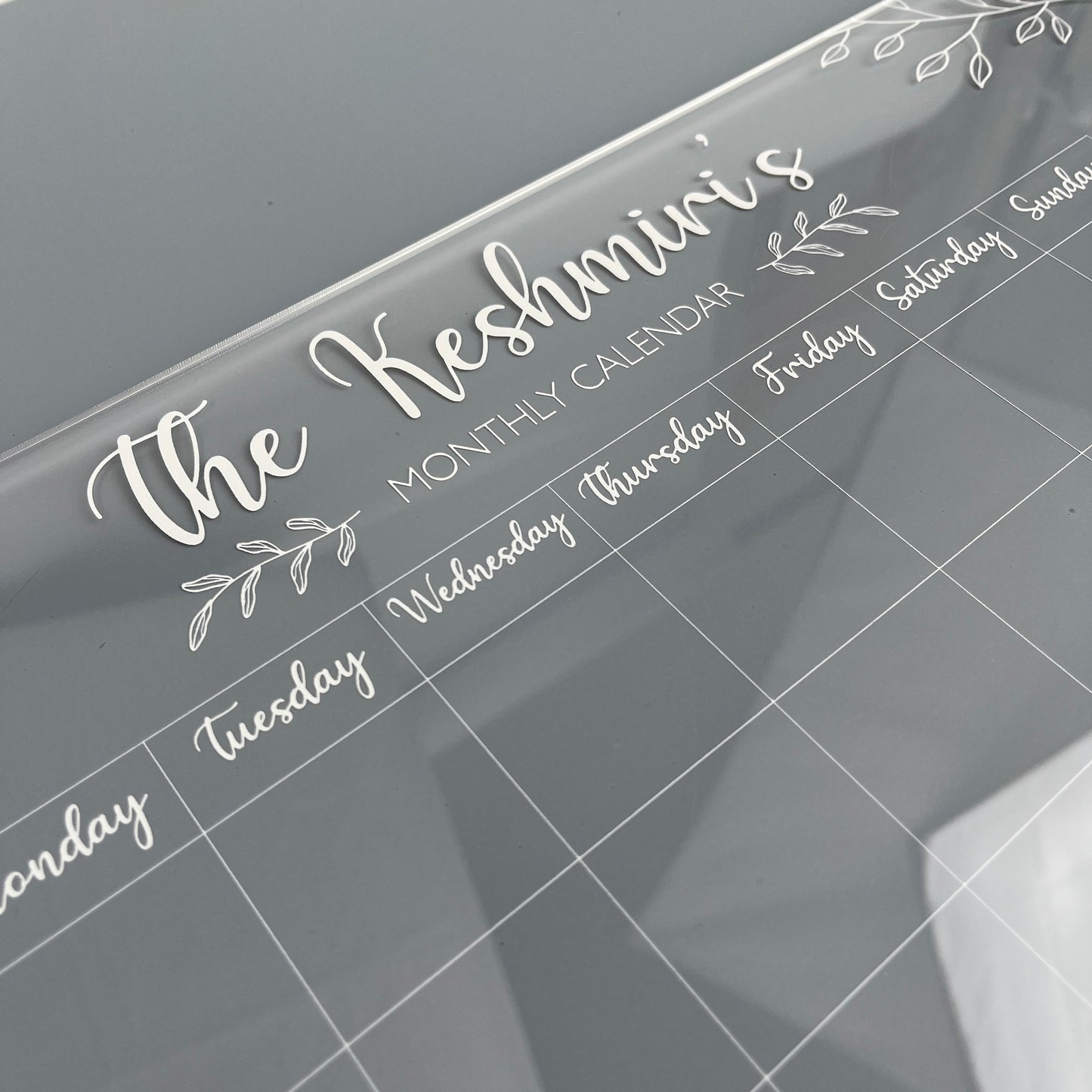 Monthly calendar with 'The Keshmiri's' in white writing on clear acrylic