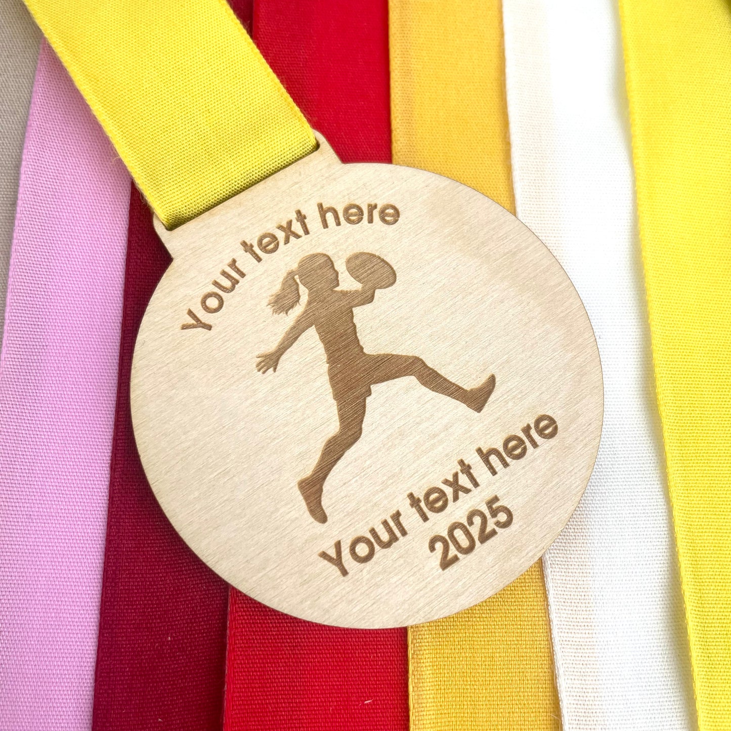 eco-friendly wooden rugby medal with customisable text and a silhouette of a rugby player on a colorful ribbon background.
