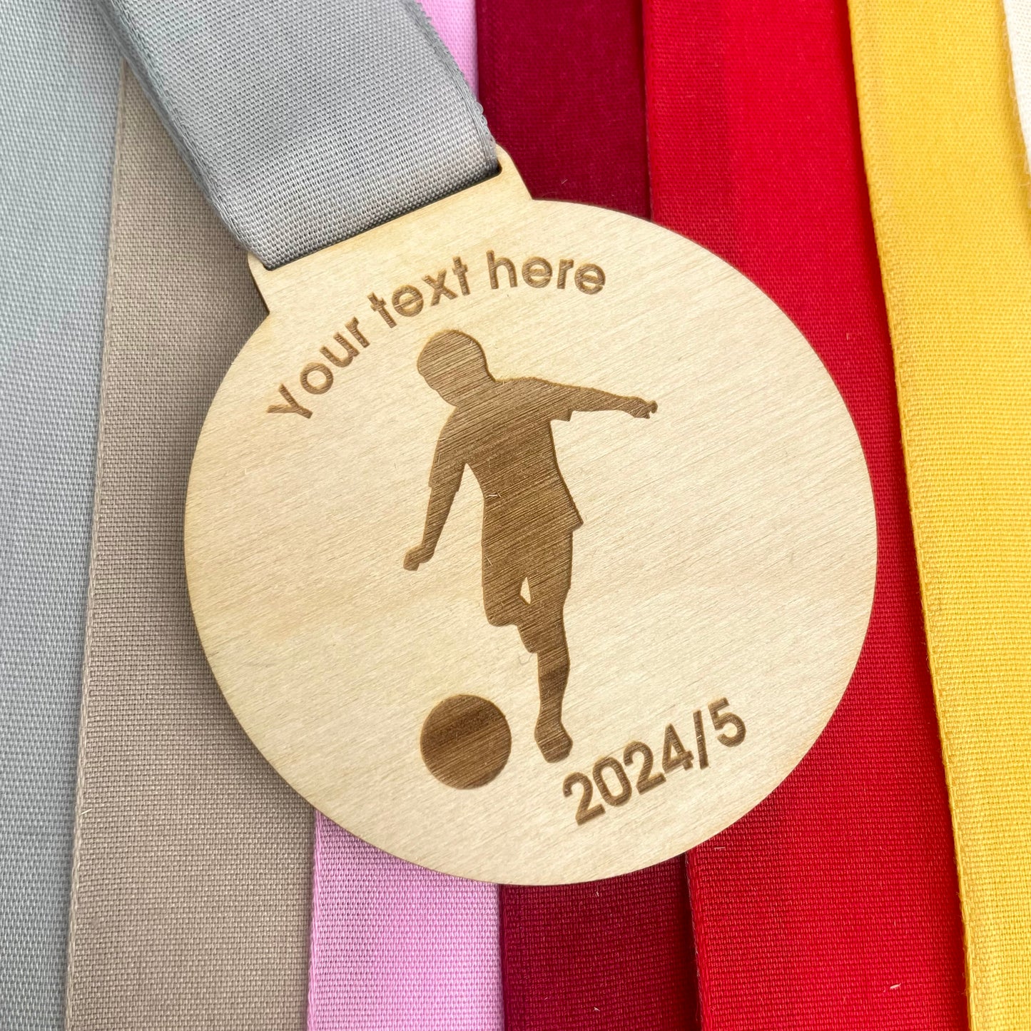 Wooden medal with a football player silhouette and customisable text on a colorful ribbon background