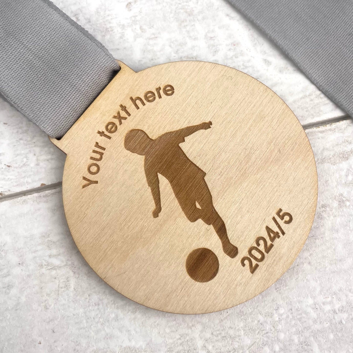 Wooden medal with a silhouette of a person kicking a ball, text placeholder, and date.