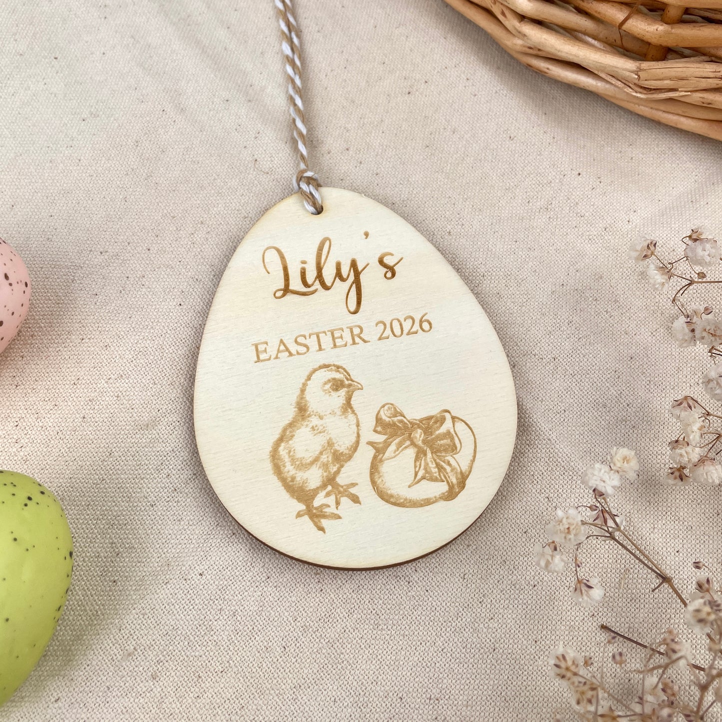Wooden Easter egg decoration with 'Lily's Easter 2026' engraving and chick illustration, held in a hand.