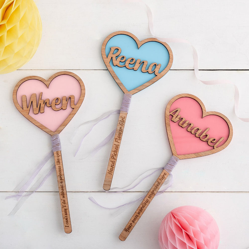 pink and blue heart shaped flower wands with sat on a white wooden background with some party decorations  