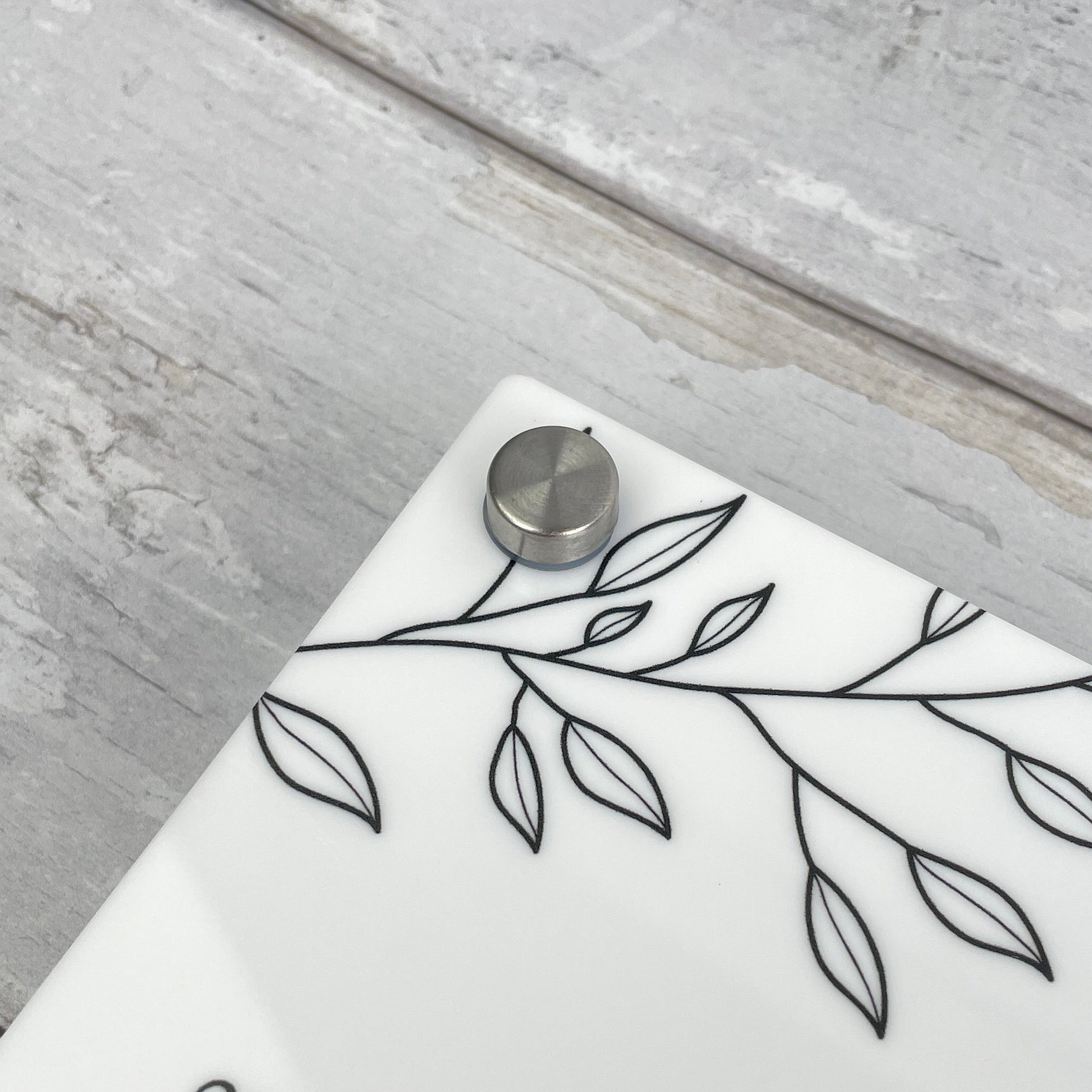 Metal fixings on a weekly planner - white acrylic with black text