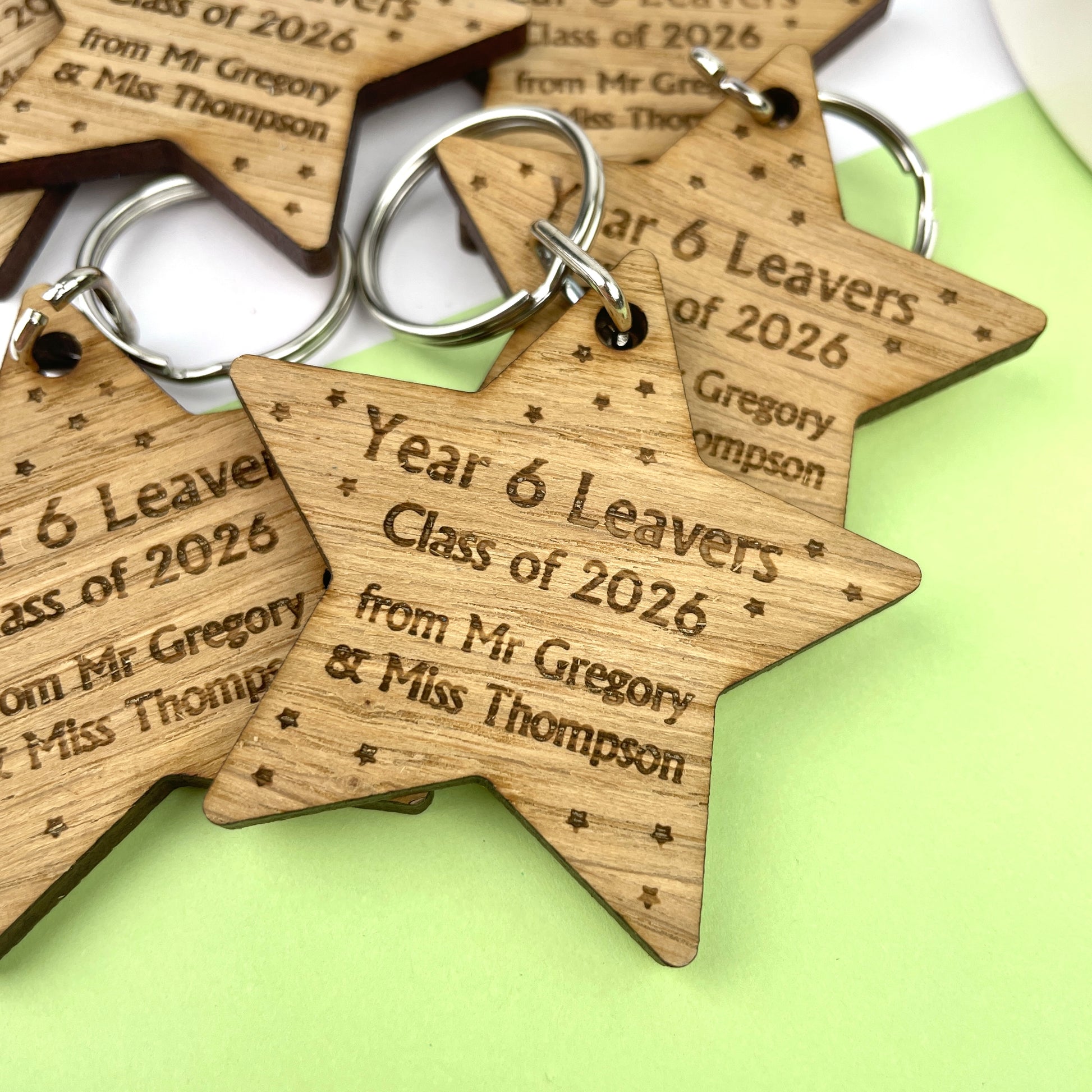 A wooden star-shaped keyring with engraved text celebrating 'Year 6 Leavers' and 'Class of 2026', along with the names of the school and teacher.