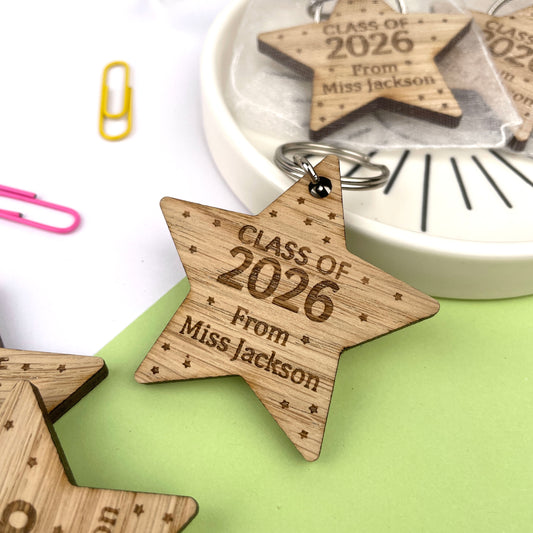 A wooden star-shaped keyring with engraved text celebrating 'Class of 2026', along with the name of the teacher.