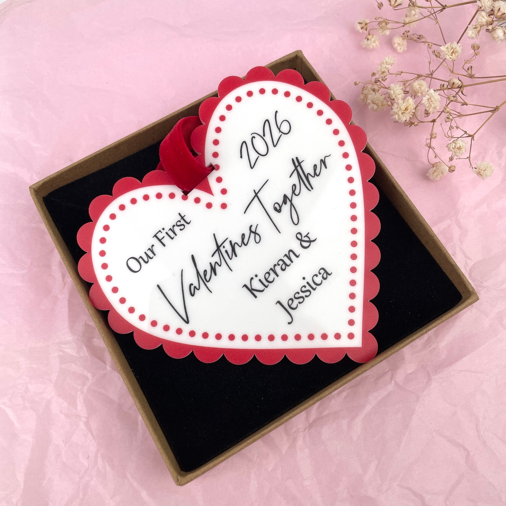 White and red acrylic printed valentines day heart customised with 'Our first valentines together 2026' 'Kieran & Jessica'. In a brown kraft gift box. Made by The Bespoke Workshop.