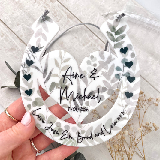 Eucalyptus design horseshoe design with printed names being held up by hands with a floral background front shot