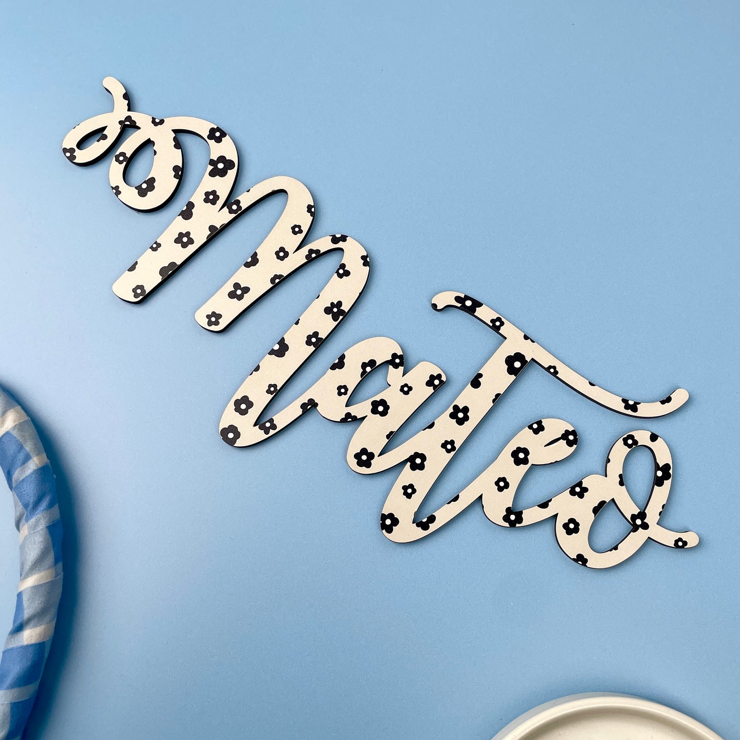 Decorative wall art with 'mateo' text on a light blue background