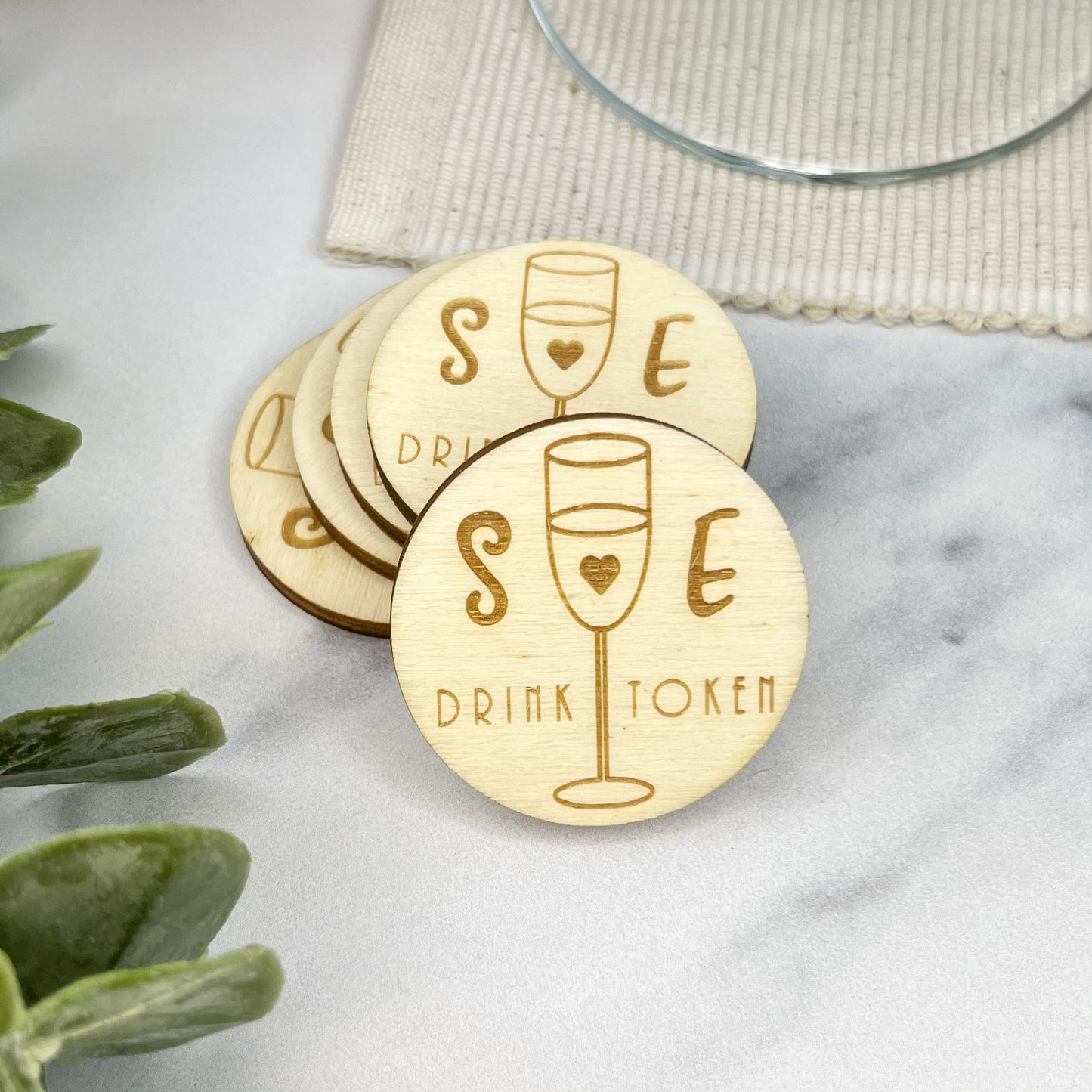 Round rustic wooden personalised wedding drinks tokens which has the couples initials engraved by The Bespoke Workshop