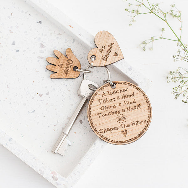 personalised wooden teacher gift keyring with one heart and hand charm on white stone with flowers